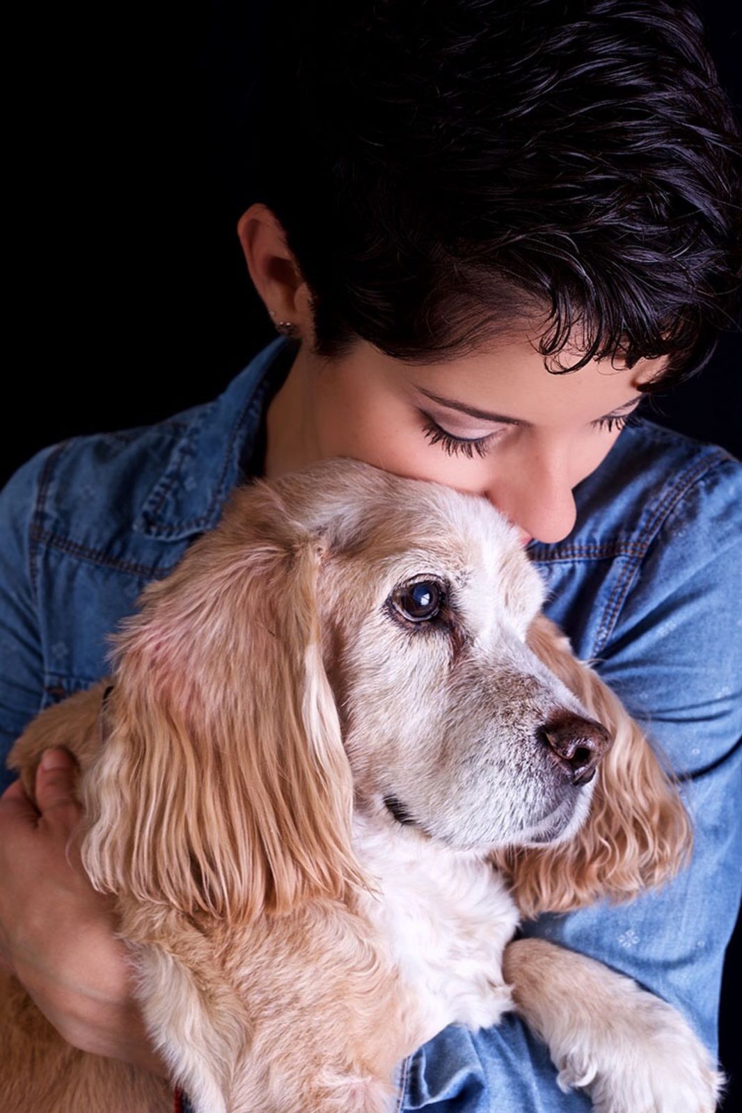 Mujer con los ojos cerrados abrazando a un cocker spaniel