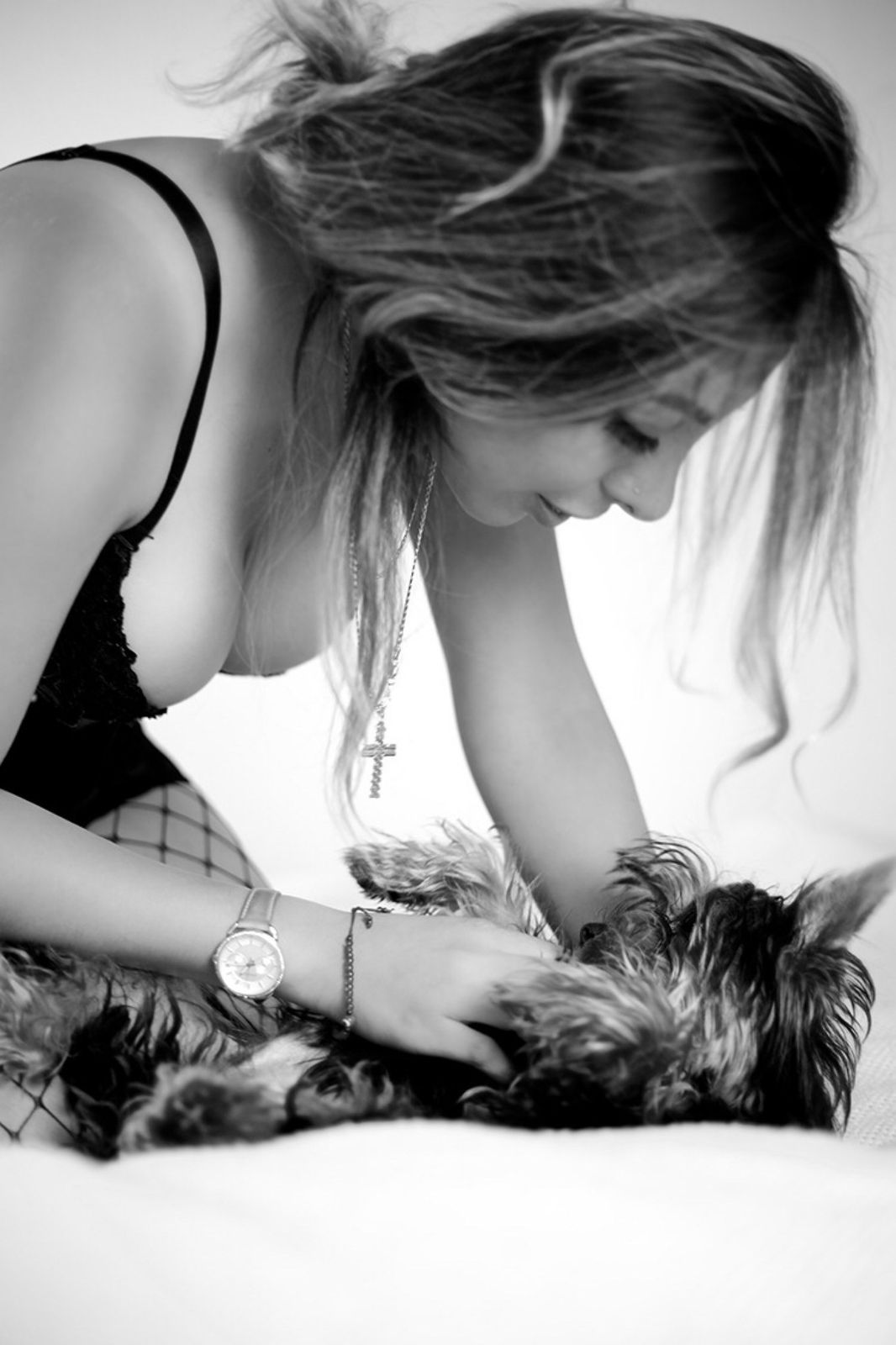 Mujer inclinada sobre un yorkshire en la cama, blanco y negro