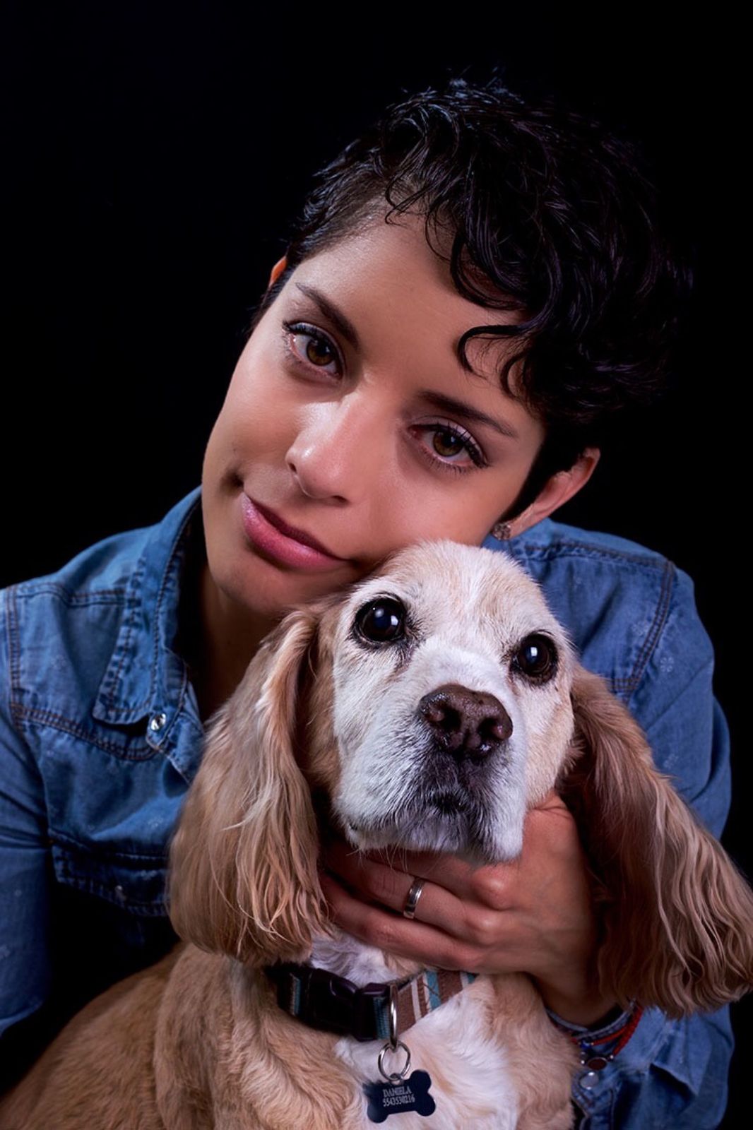 Mujer de camisa de mezclilla abrazando a un cocker spaniel