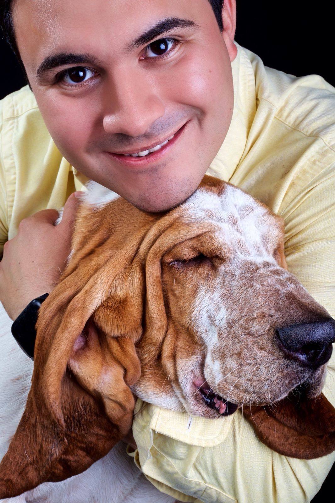 Hombre de camisa amarilla con un basset hound dormido en el pecho
