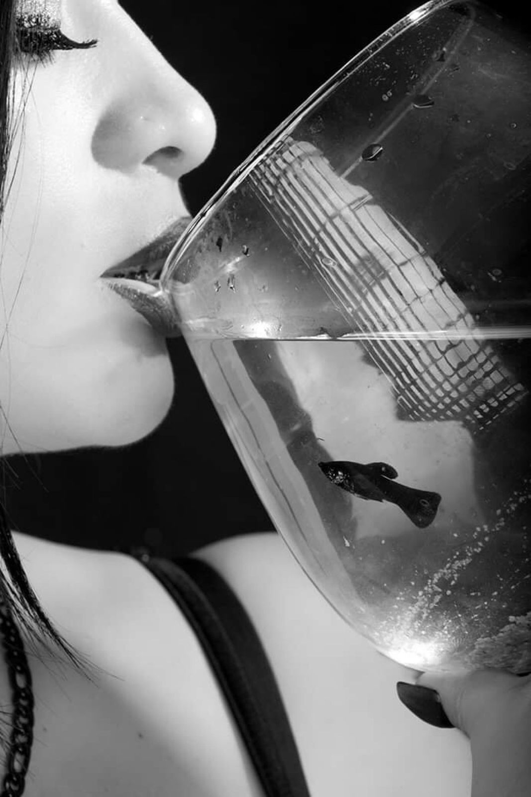 Perfil de una mujer besando una pecera con un pez, blanco y negro